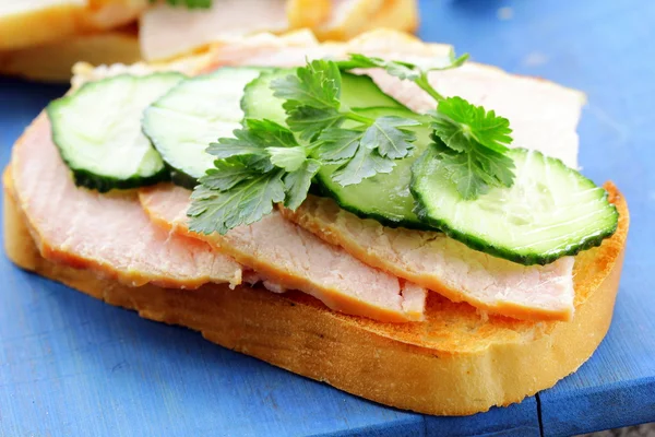 Sandwich with ham and cucumber on the wooden cutting board — Stock Photo, Image