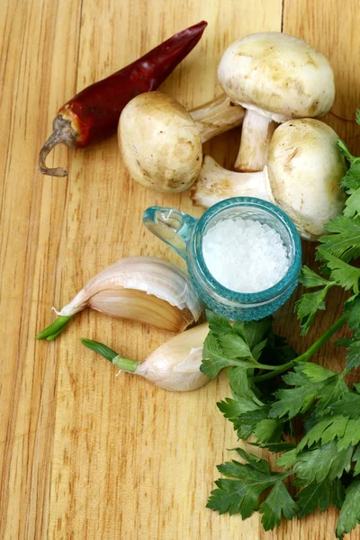 Knoflook, champignons, chili peper, peterselie, komkommer en specerijen op een snijplank — Stockfoto