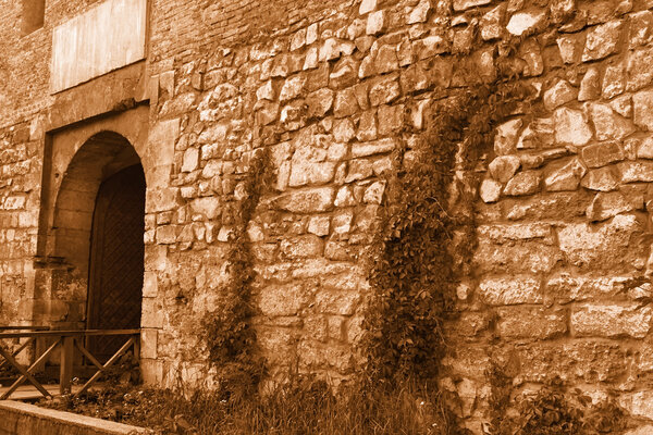 Fragment the medieval stone wall with an iron gate in Lviv, Ukraine. Sepia