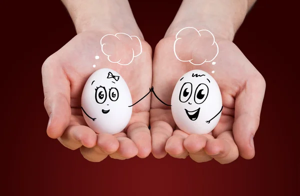 Αρσενικό χέρι που κρατά εκμετάλλευση αυγά με χαμογελαστά πρόσωπα — Φωτογραφία Αρχείου