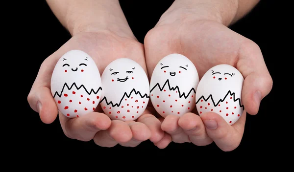 Mano tenendo carino uova con divertente faccia smileys — Foto Stock