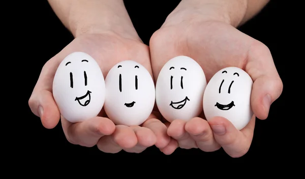 Mão segurando bonito ovos com engraçado rosto smileys — Fotografia de Stock