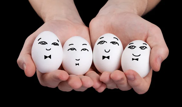 Рука держит милые яйца с смешными улыбками на лице — стоковое фото