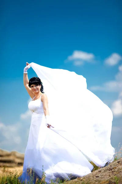 Schöne Braut auf dem Boden vor blauem Himmel. — Stockfoto