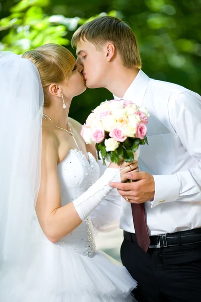 Braut und Bräutigam mit einem Strauß Küsse — Stockfoto