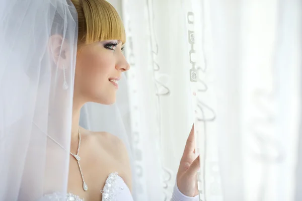 Очаровательная молодая невеста смотрит в окно — стоковое фото