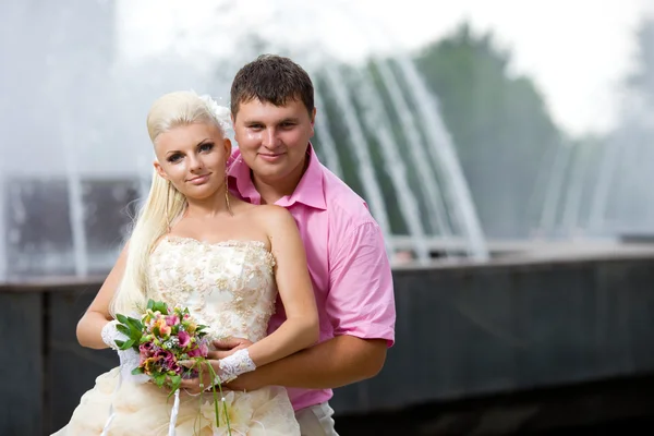 Förtjust brudgummen och bruden mot en fontän. — Stockfoto