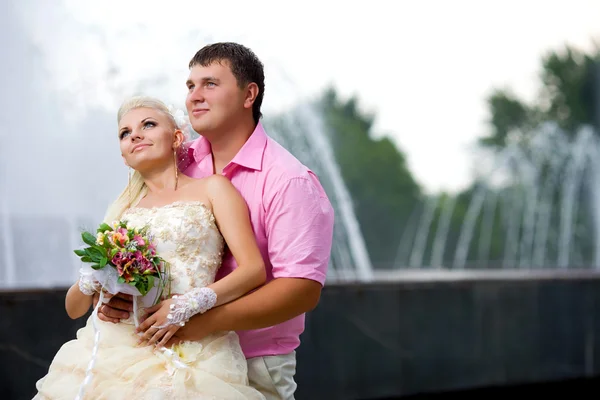Förtjust brudgummen och bruden mot en fontän. — Stockfoto