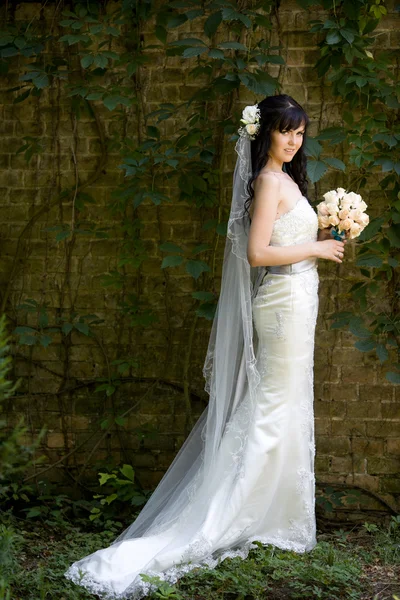 Красивая молодая невеста с букетом на природе — стоковое фото