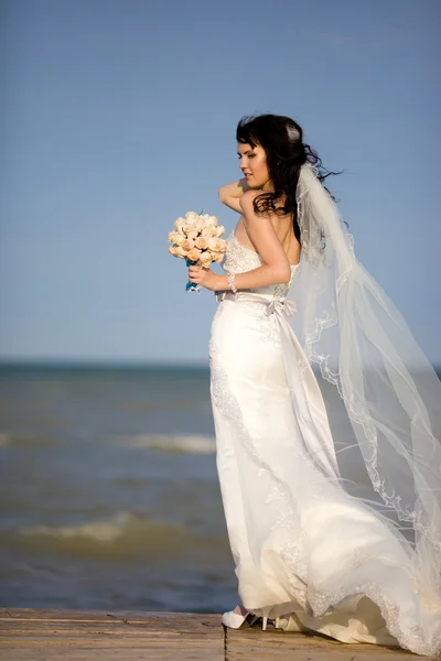 Όμορφη νεαρή νύφη με μια ανθοδέσμη στη θάλασσα — Φωτογραφία Αρχείου