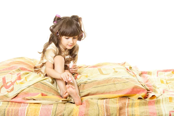 A little girl sitting on a bed — Stock Photo, Image