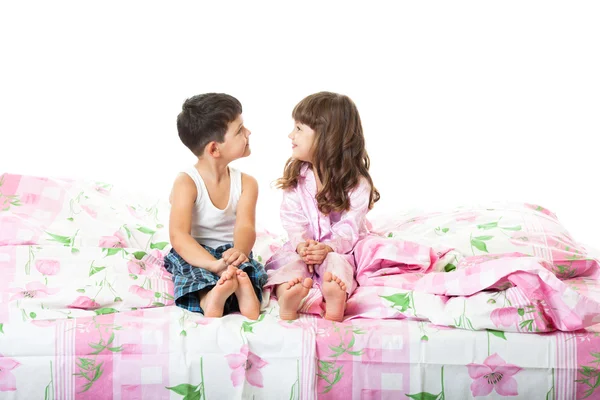 Kis lány és egy fiú ült az ágyon Jogdíjmentes Stock Képek