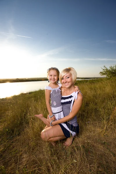 Mother and daughter playing at the river bank — Stock Photo, Image