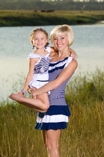 Mother and daughter playing at the river bank — Stock Photo, Image