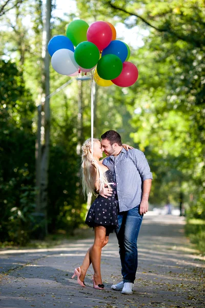 Jovem casal amoroso com balões no fundo natural — Fotografia de Stock