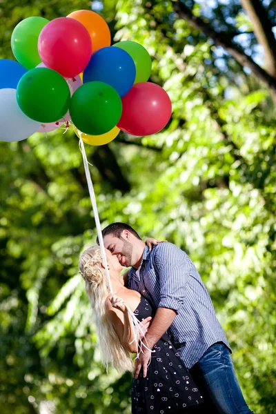Jovem casal amoroso com balões no fundo natural — Fotografia de Stock