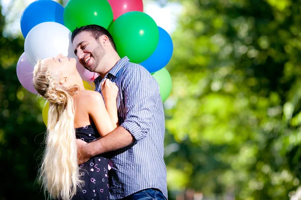 Mladí milující pár s balonky na přírodní pozadí — Stock fotografie