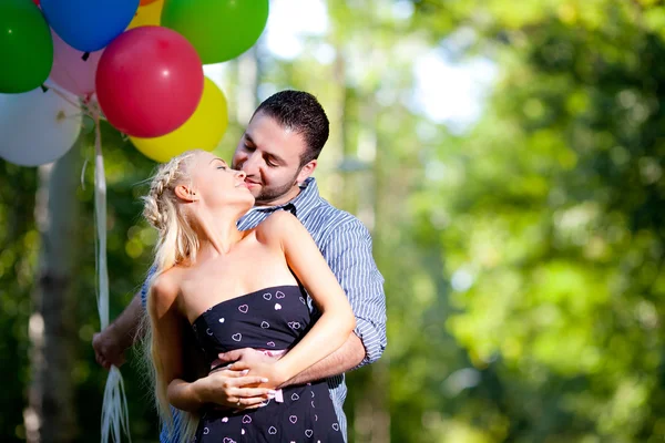 Jonge liefdevol paar met ballonnen op natuurlijke achtergrond — Stockfoto