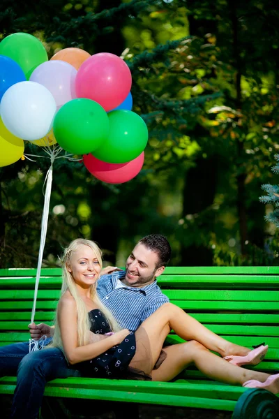 Junges Liebespaar mit Luftballons auf natürlichem Hintergrund — Stockfoto