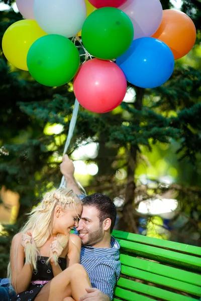 Junges Liebespaar mit Luftballons auf natürlichem Hintergrund — Stockfoto