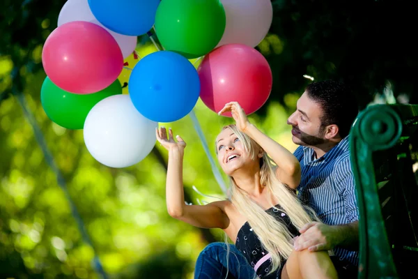 Joven pareja amorosa con globos sobre fondo natural — Foto de Stock