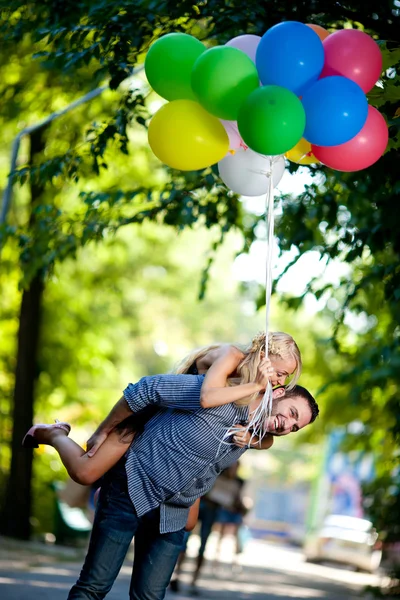 Jonge liefdevol paar met ballonnen op natuurlijke achtergrond — Stockfoto
