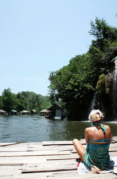 Junge Frau entspannt sich auf einem Hausboot in der Nähe des Wasserfalls. — Stockfoto