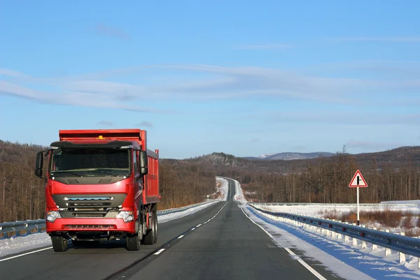 De rode vrachtwagen op een winter weg. — Stockfoto