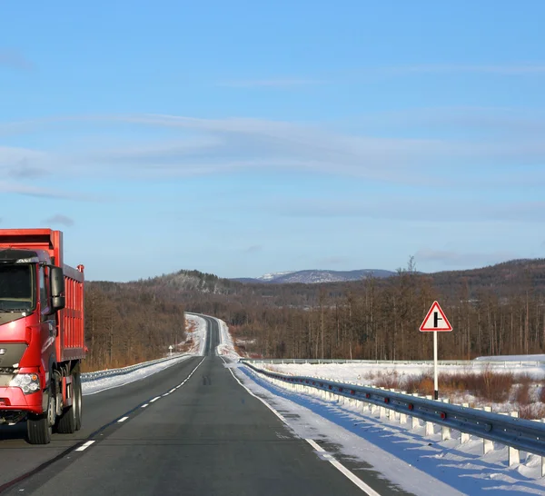 Bir kış yolda kırmızı kamyon. — Stok fotoğraf