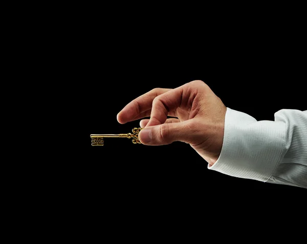 Mão humana segurando chave dourada — Fotografia de Stock