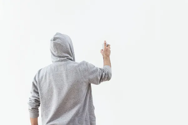 Молодой человек брызгает краской на стену — стоковое фото