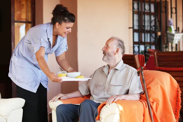 Oudere senior gebracht maaltijd door verzorgers of verpleegkundige — Stockfoto