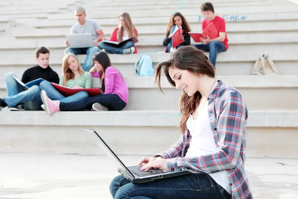 Estudiantes trabajando con computadoras portátiles y libros en el campus —  Fotos de Stock