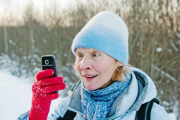 La donna fotografa su un telefono cellulare in inverno a piedi — Foto Stock