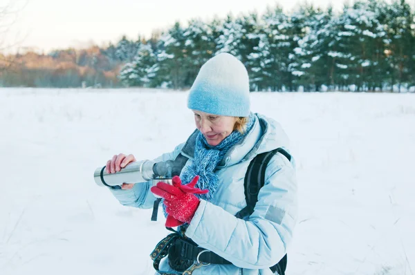 Kobieta wylewa z termosem herbaty, w zimie na spacer — Zdjęcie stockowe