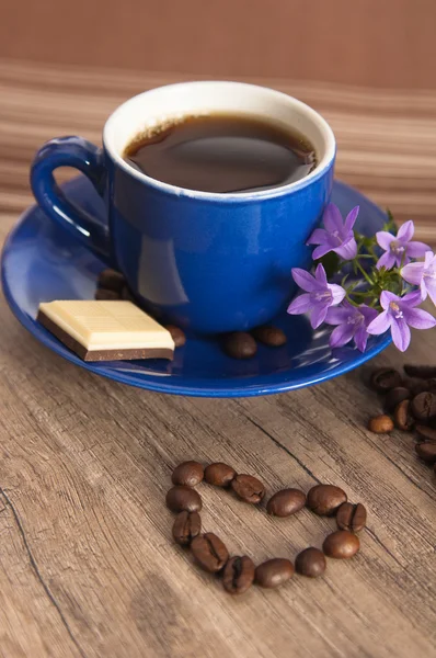 Cup of coffee with beans on old wooden surface — Stock Photo, Image