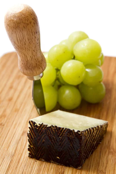 Manchego ost ang druvor på skärbräda Stockbild
