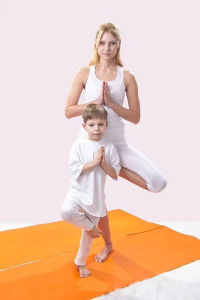 Красивая молодая мать практикует йогу со своим сыном — стоковое фото