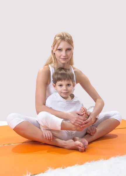 一个美丽的年轻母亲与她的儿子做法瑜伽 — 图库照片