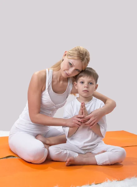 A beautiful young mother practices yoga with her son — Stock Photo, Image