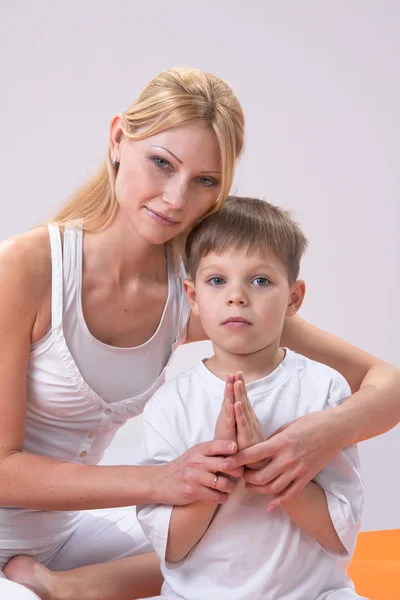 A beautiful young mother practices yoga with her son — Stock Photo, Image