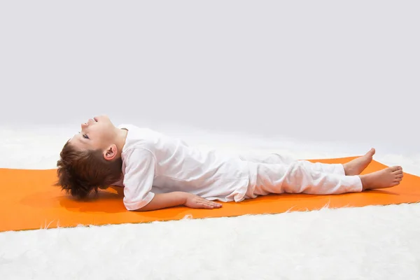 Kinderen van yoga. de kleine jongen oefent. — Stockfoto