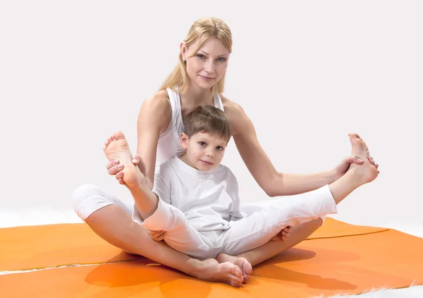 Una hermosa madre joven practica yoga con su hijo — Foto de Stock