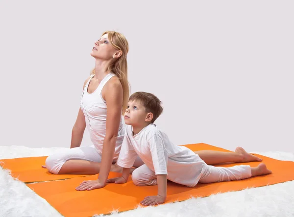Uma bela jovem mãe pratica ioga com seu filho — Fotografia de Stock