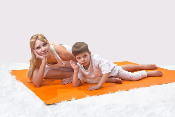 Eine schöne junge Mutter praktiziert mit ihrem Sohn Yoga — Stockfoto