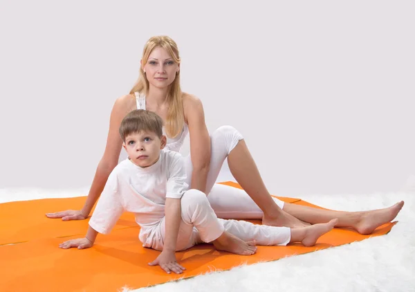 Uma bela jovem mãe pratica ioga com seu filho — Fotografia de Stock
