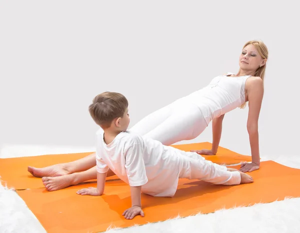 Una hermosa madre joven practica yoga con su hijo — Foto de Stock