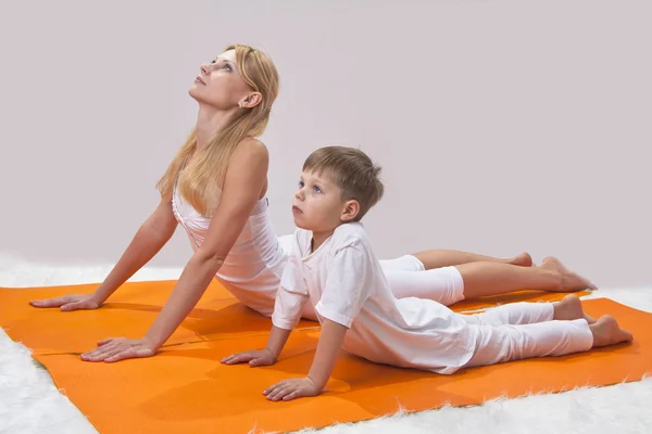 Een mooie jonge moeder praktijken yoga met haar zoon — Stockfoto