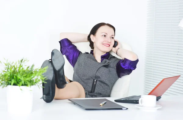 Mujer de negocios hablar por teléfono con las piernas en la mesa —  Fotos de Stock