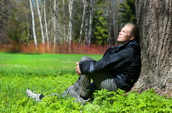 Hombre sentado en el parque bajo el árbol — Foto de Stock